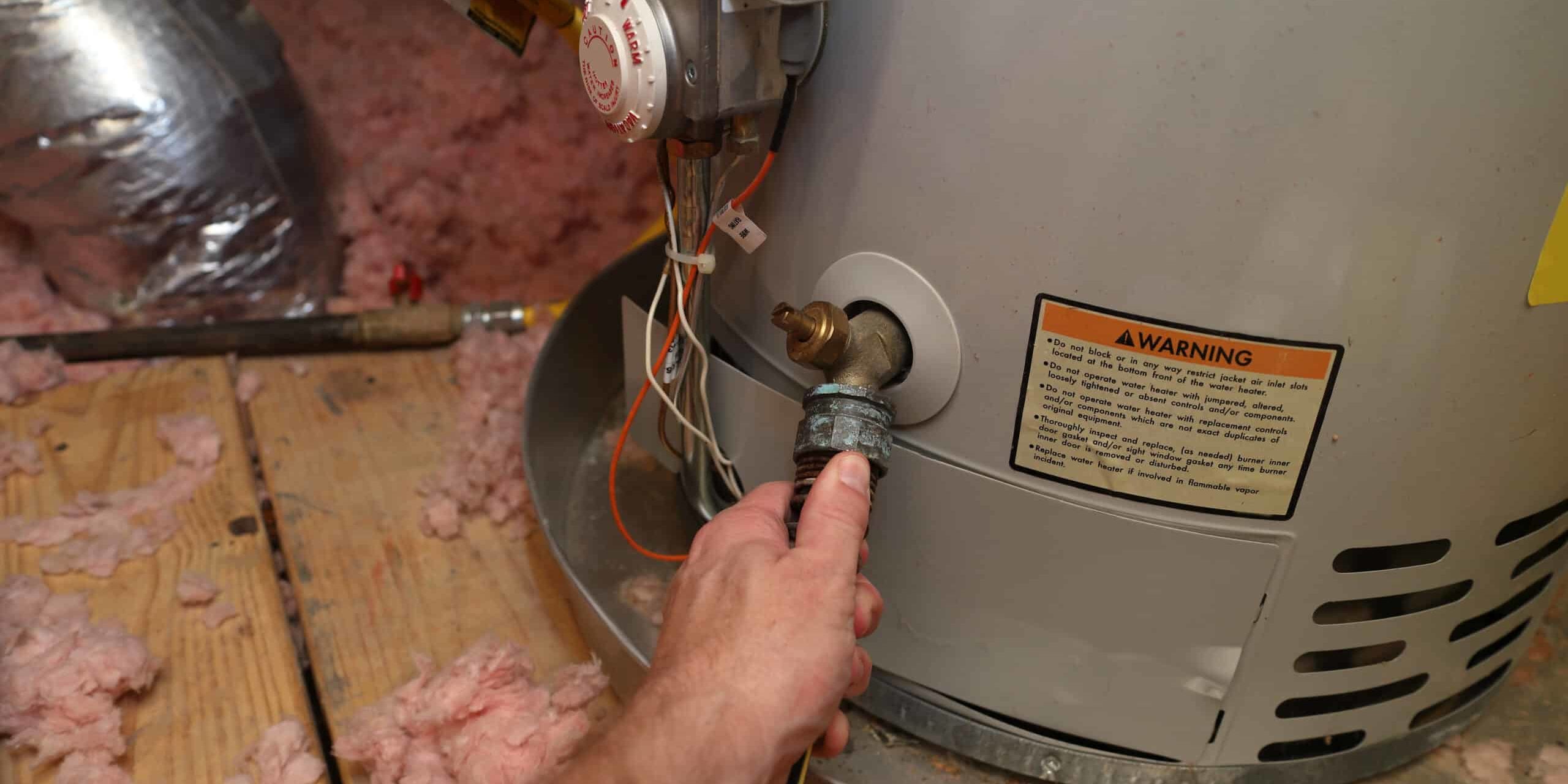 Hand attaches hose to drain water heater